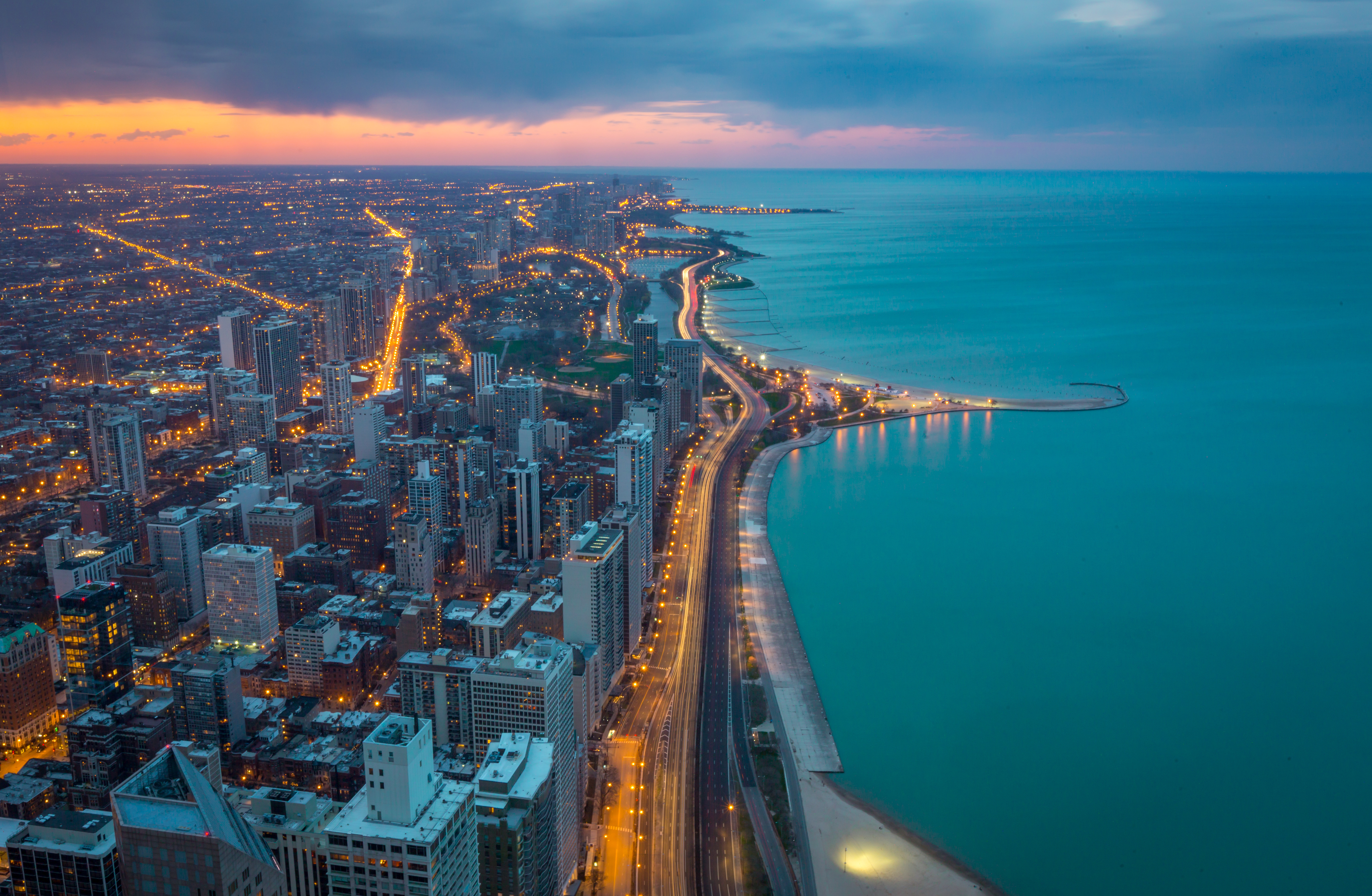 Aerial twilight view of Chicago's downtown skyline and Lake Michigan coastline with illuminated streets