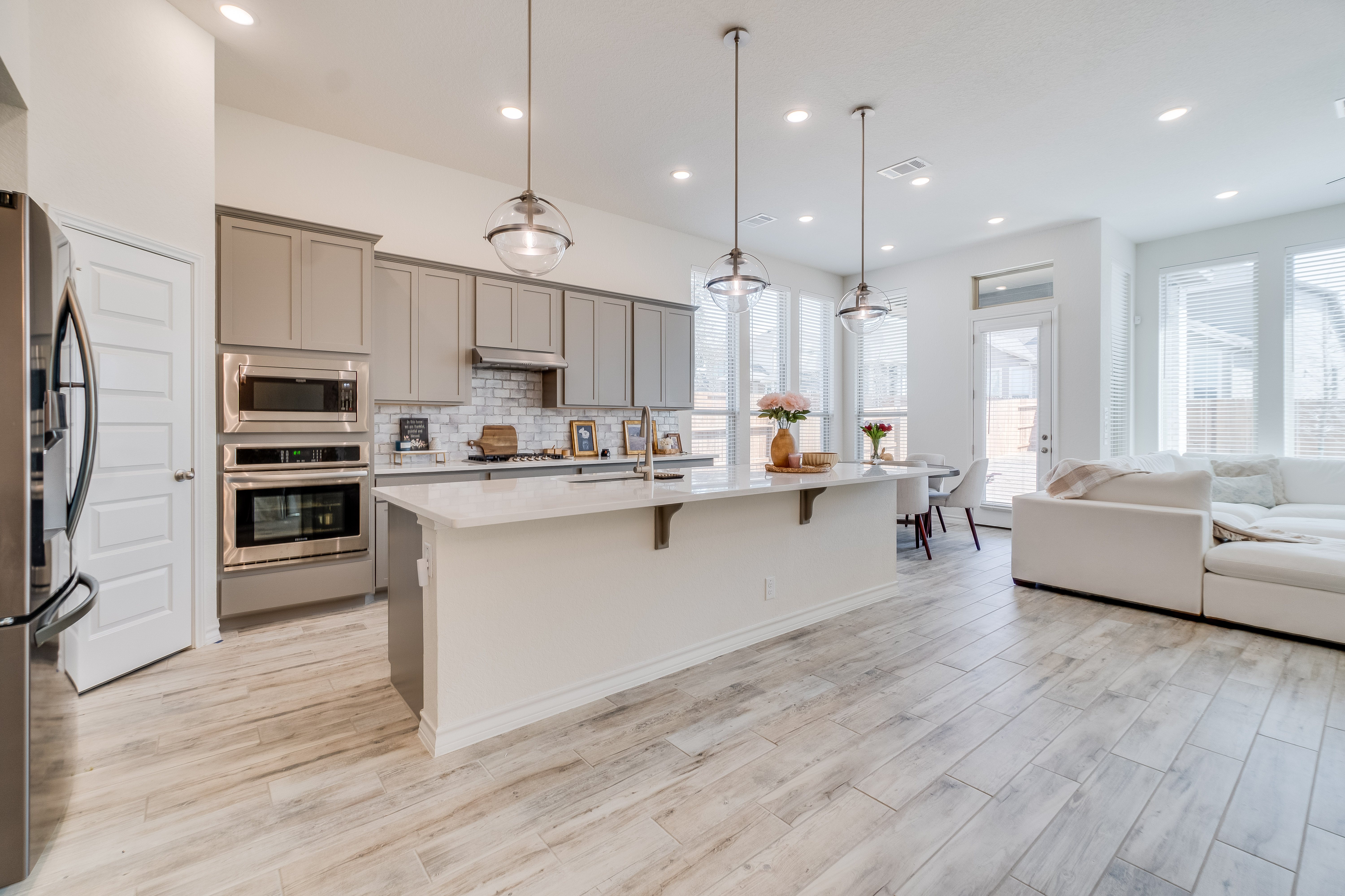 Modern kitchen with white island, gray cabinets, stainless steel appliances, and pendant lighting