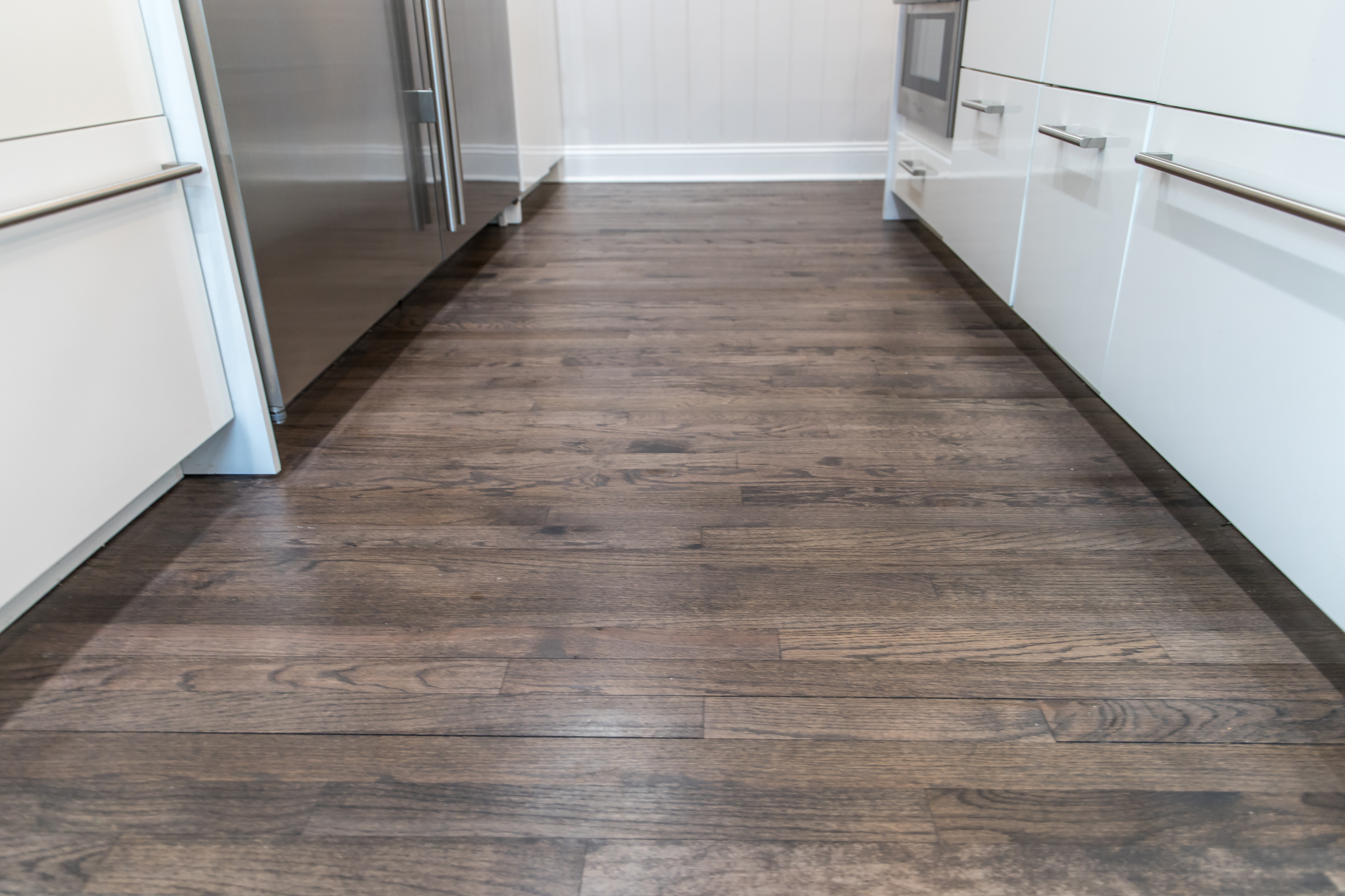 Modern kitchen with dark wood flooring and white cabinetry